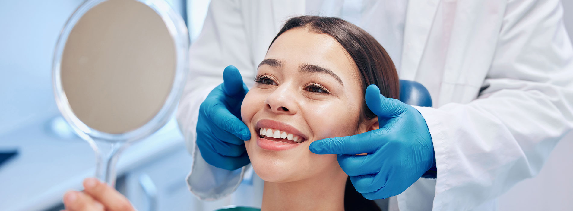 A person receiving dental care in a professional setting, with a dentist performing an examination using a mirror.