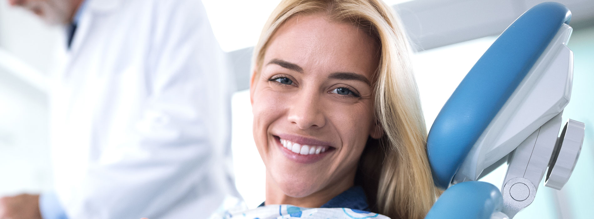 A woman in a dental chair with a smile, receiving dental care from a professional.