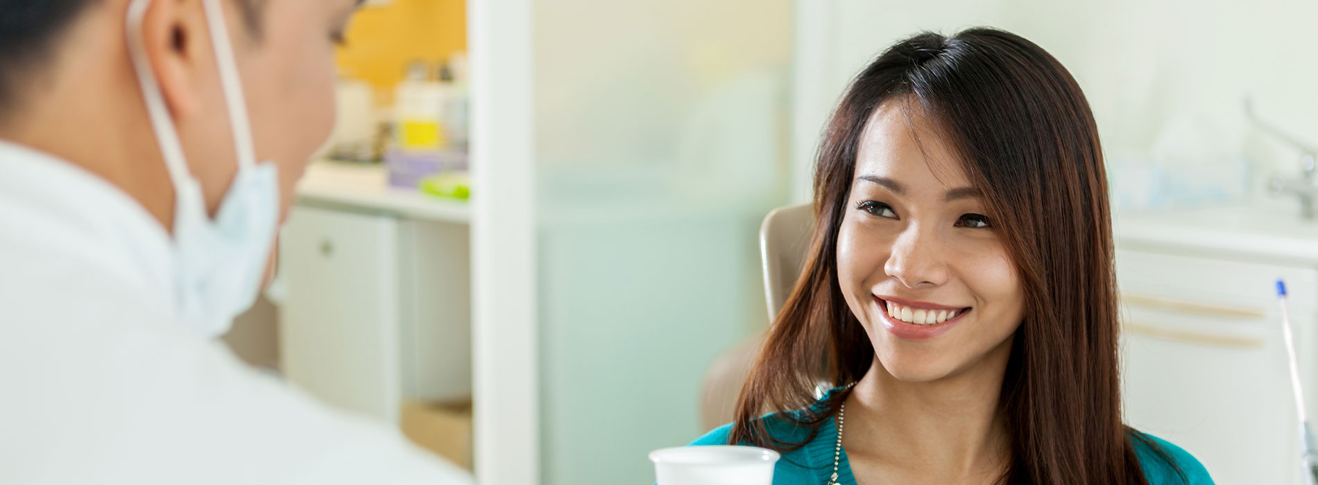 A woman in a dental office, smiling and engaging with a dental professional.