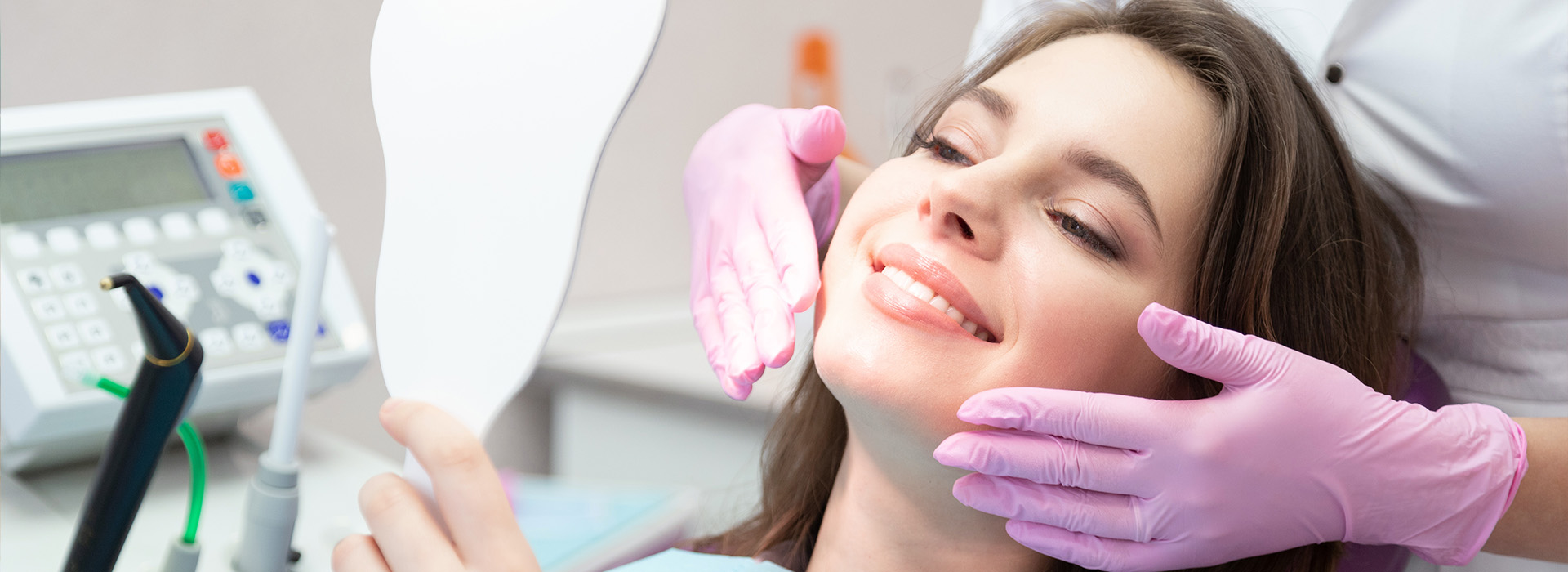 A woman receiving dental care, with a dentist using a mirror to examine her teeth.