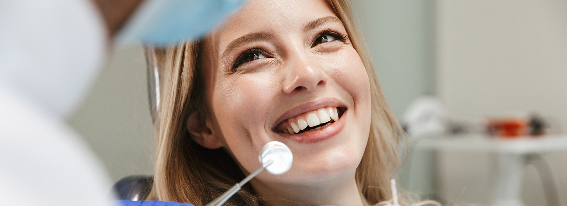 A woman in a dental chair with a smile, receiving dental care from a professional.