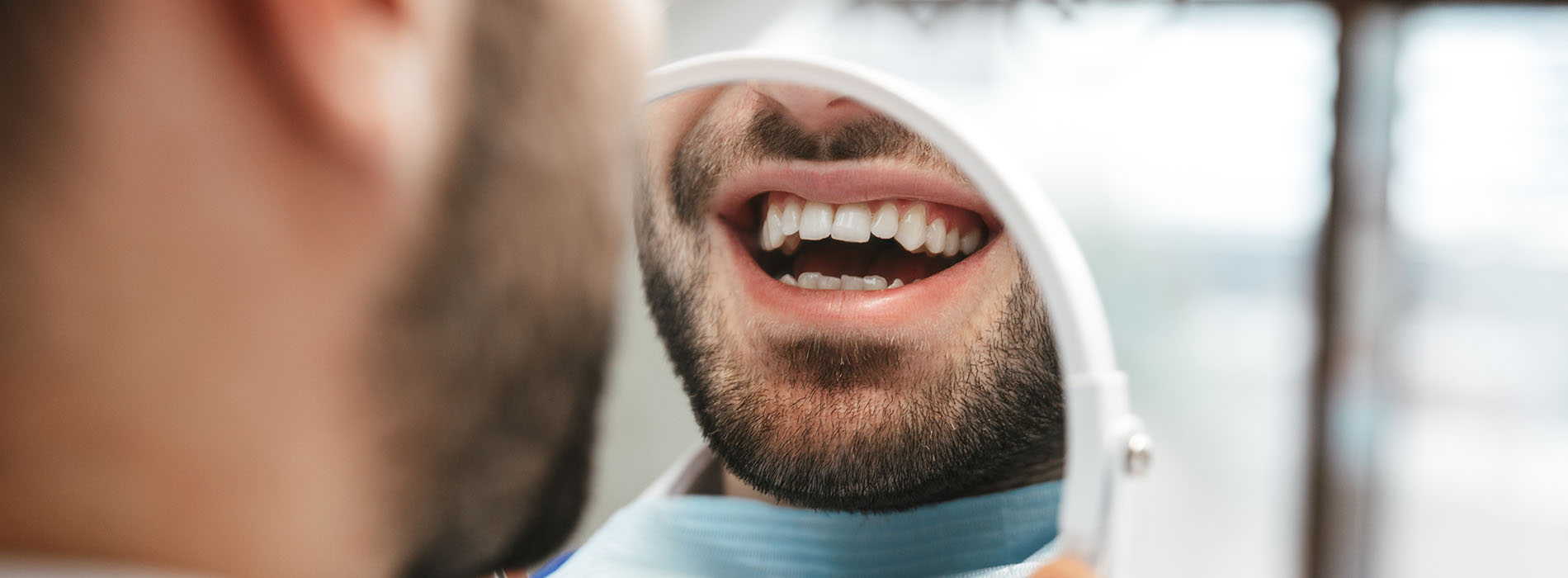 A man in a dental office, holding his mouth open during an examination.