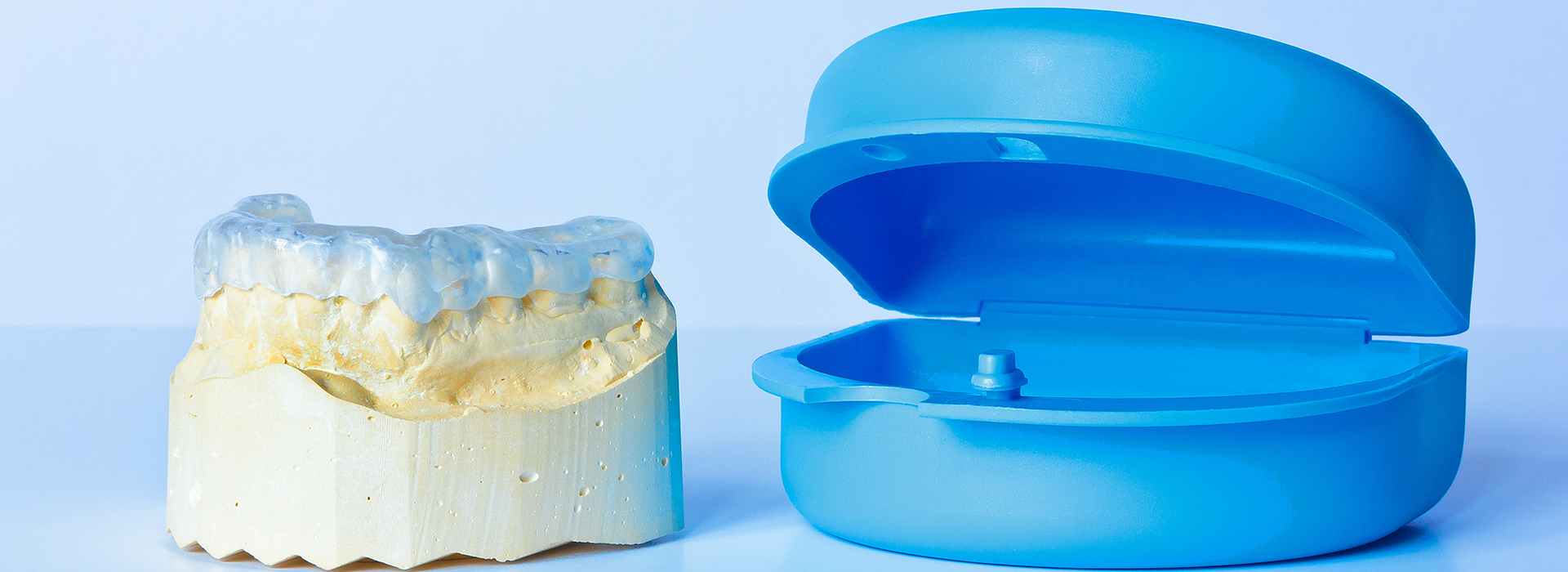 A blue dental implant and a yellow tooth modeled on a white base, both displayed against a light background.