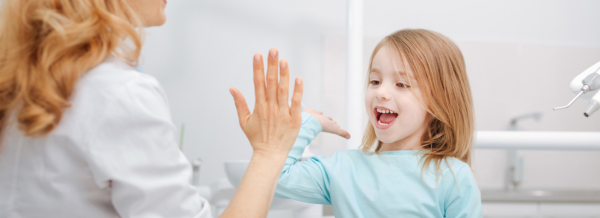 A woman and a young girl in a bathroom, with the child holding up her hand towards the camera.