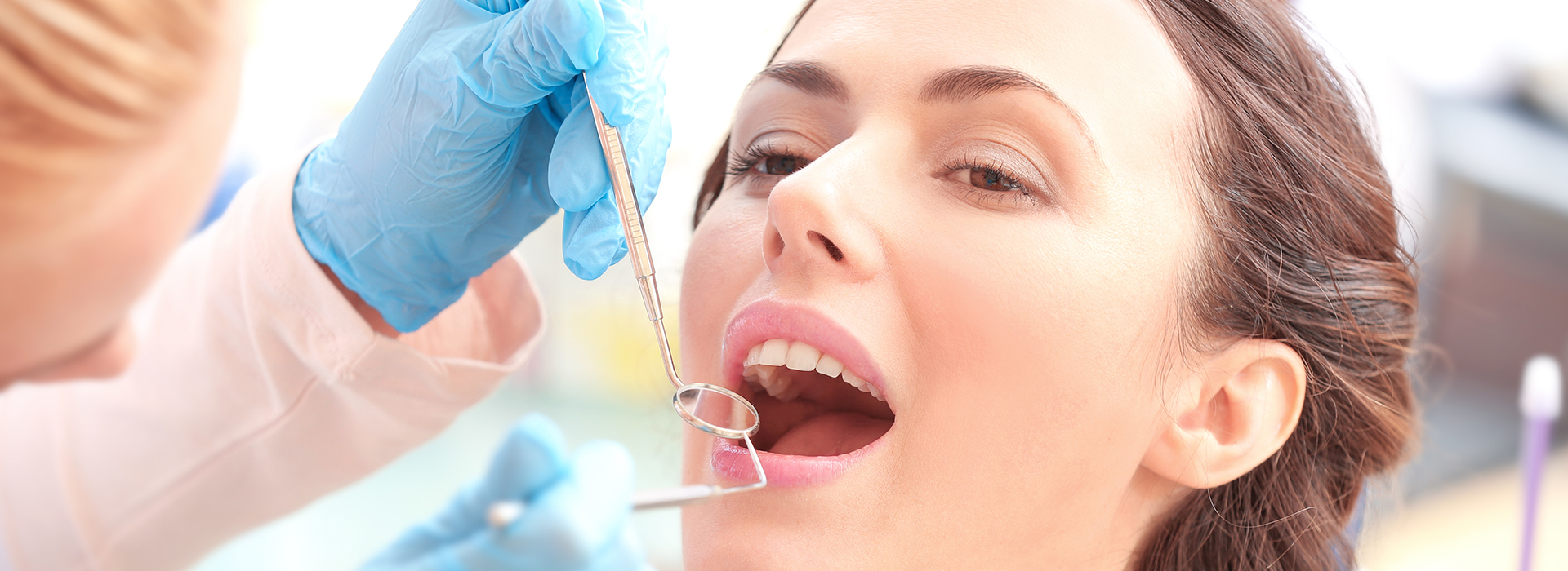 Woman receiving dental implant procedure, with dental implant being inserted by dentist.