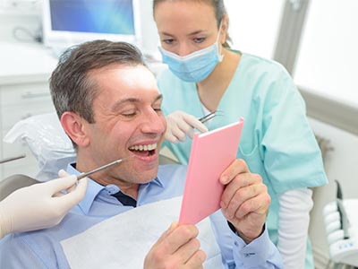 Man holding a pink card in front of his face, surrounded by dental professionals.