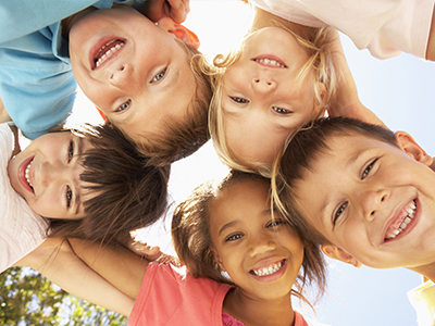 A group of children, possibly siblings, smiling and posing for a photo with their arms around each other.