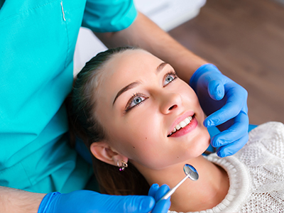 A woman receiving dental care with a dentist performing the procedure.