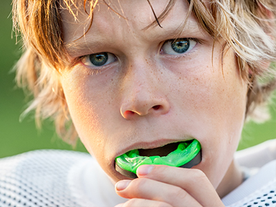 A young male with blonde hair, wearing a football uniform and holding a toothbrush in his mouth.