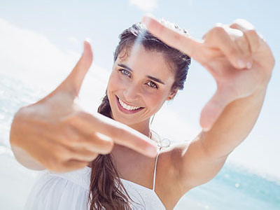 The image shows a woman taking a selfie with her hand in front of her face, capturing the moment with a camera.